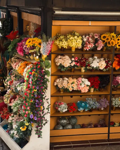 A kiosk packed floor to ceiling with bright artificial flowers